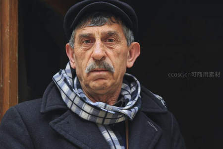 戴鸭舌帽的老人凝视前方神情严肃
