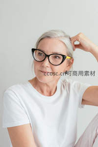 白发女士轻抚发丝展露温柔笑容