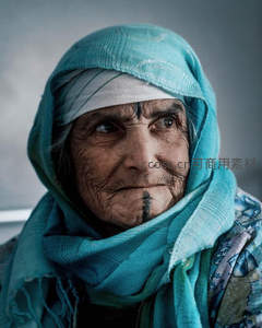 蓝巾裹头纹面老妇凝重目光