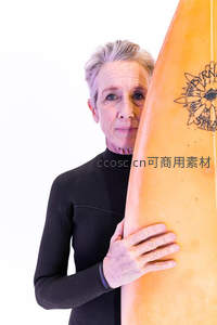 冲浪奶奶怀抱橙色冲浪板，眼神坚定充满活力