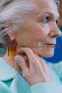 银发长者轻抚耳畔，彩色耳环点缀优雅时光