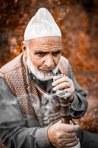 白帽老者专注抽水烟的瞬间
