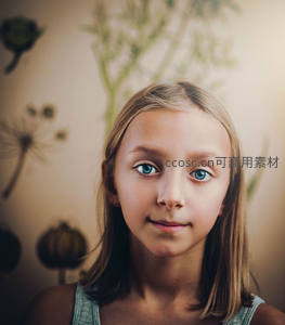 蓝眸少女凝视镜头，背景植物朦胧