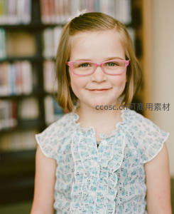 戴粉框眼镜的女孩在图书馆微笑