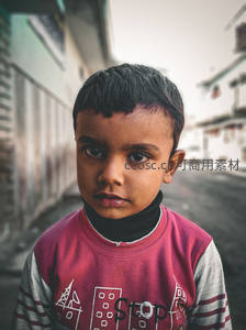 街头男孩严肃凝视，背景巷弄斑驳