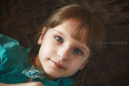 蓝眼女孩仰卧微笑，发辫轻柔可爱