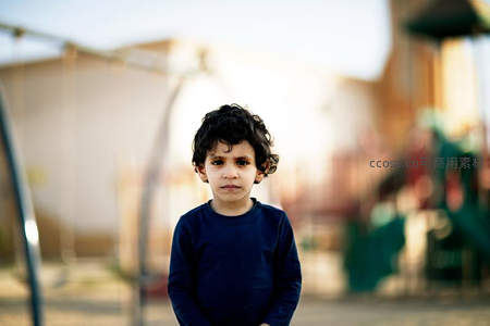 游乐场中卷发男孩的凝重表情