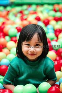 绿衣女孩在彩色海洋球中微笑