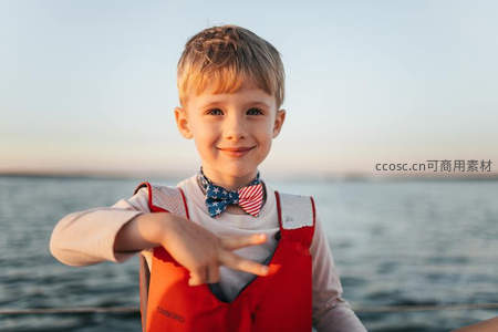 穿救生衣的小男孩在船上比耶