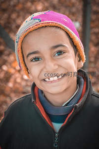笑颜如花孩童戴彩帽，秋叶背景暖意融融