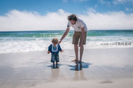 父亲牵着孩子在海边沙滩漫步