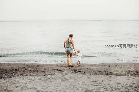 母子牵手漫步海边，背影尽显宁静温情
