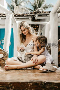母女与猫咪在热带庭院共享温馨时光