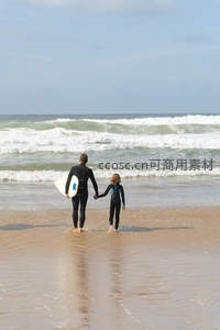 父子手牵手走向海浪准备冲浪冒险