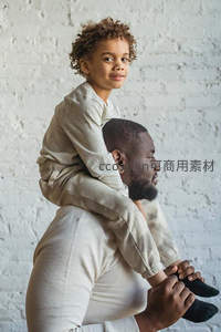 父亲肩头驮着卷发萌娃，温情侧影定格幸福