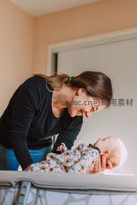 妈妈温柔俯身逗弄婴儿，满眼爱意流淌