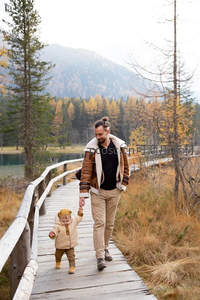 木桥上父女携手漫步秋林