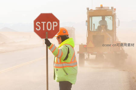 交通指挥员手持停车标志引导施工车辆