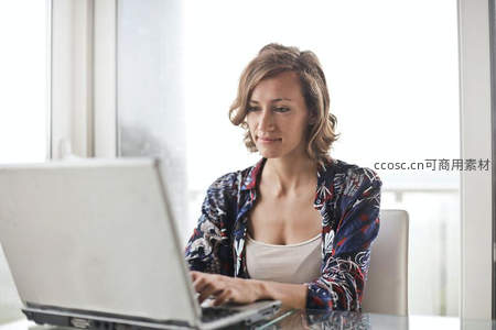 窗边女子专注使用笔记本电脑