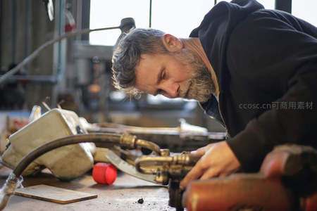 技师俯身调试复杂机械装置