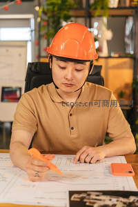 工程师戴橙帽审阅工程图纸