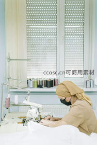 专注缝纫的女工在明亮车间工作