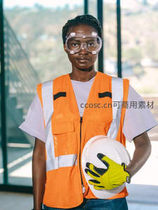 身穿橙色安全背心的女工程师手持头盔