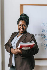 微笑女教师手持教材站在白板前