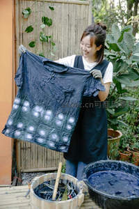 女子展示手工扎染布料笑容满面