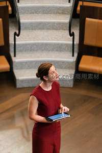 红裙女子手持平板仰望楼梯