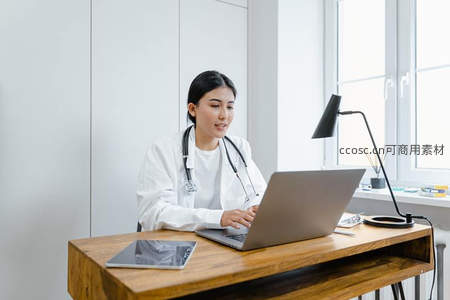 女医生在明亮诊室使用笔记本电脑工作