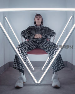 格纹套装女性坐于霓虹灯架中