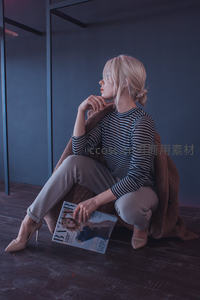 金发女子蹲坐阅读时尚杂志