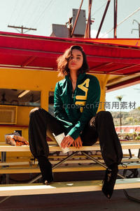 绿衣少女坐长椅，阳光洒落街头