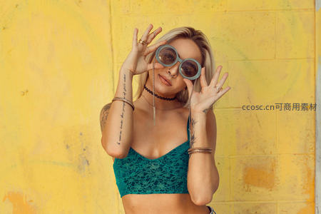 黄墙前俏皮女孩，戴墨镜比手势