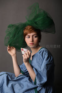 蓝裙女子头戴绿色薄纱手持花茶杯