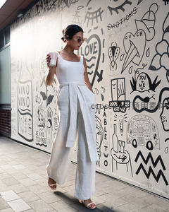 白衣女子持杯漫步涂鸦墙，简约穿搭显都市风