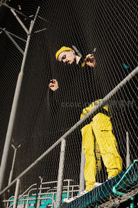 黄色工装青年攀爬铁网