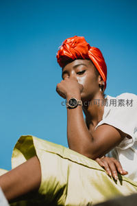 蓝天映衬下橙色头巾的沉思时刻
