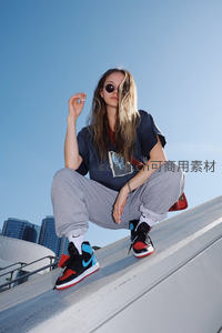 街头潮女蹲坐，蓝天映衬运动鞋