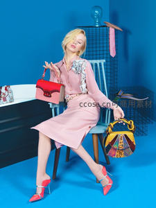 粉色套装搭配多彩手袋坐于蓝墙前