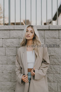 金发女子倚墙展现优雅气质
