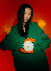 红幕前绿衣女子怀抱白花