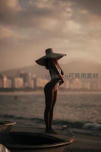 夕阳下戴宽檐帽海边女子