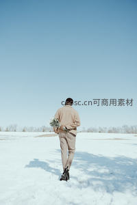雪地背影男子手捧花束前行