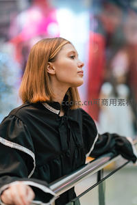 商场扶梯上金发女子凝望远方