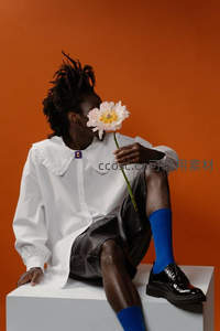 橙墙前白衬衫青年嗅花静谧时光