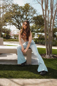 公园长椅上的时尚女性，阳光与绿意相伴