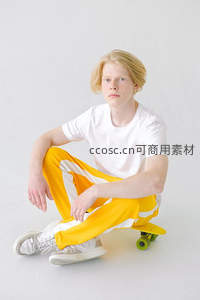 金发少年坐滑板穿黄白运动裤
