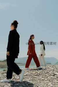 三位女性在湖畔岩石上行走